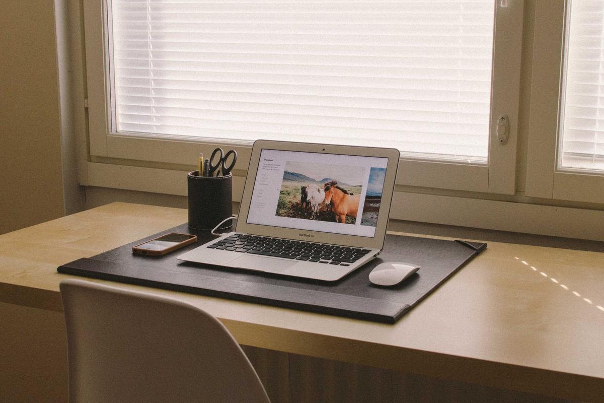 A bright desk with a laptop by a window